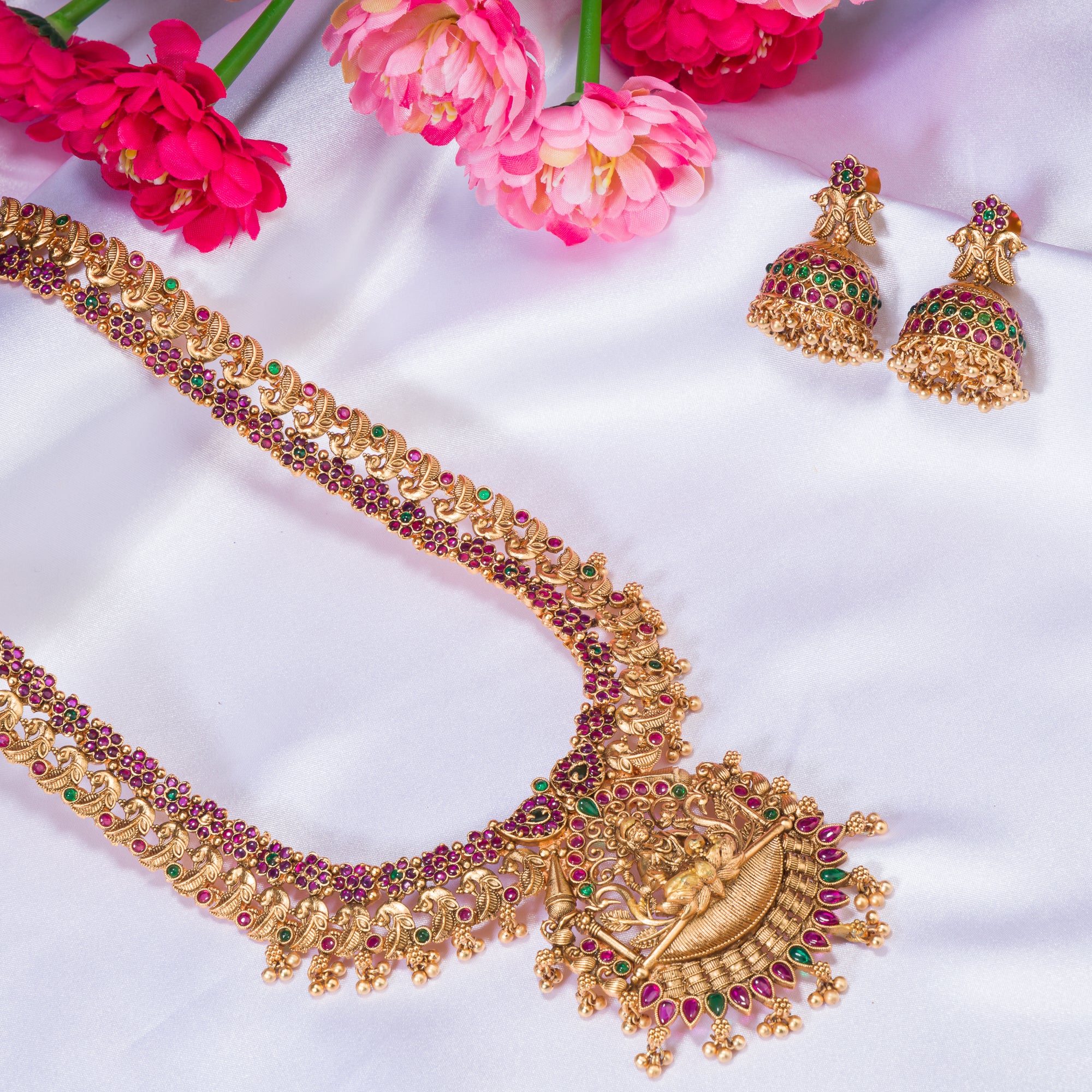 Traditional temple jewelry with red and green stones radiates timeless opulence and charm.