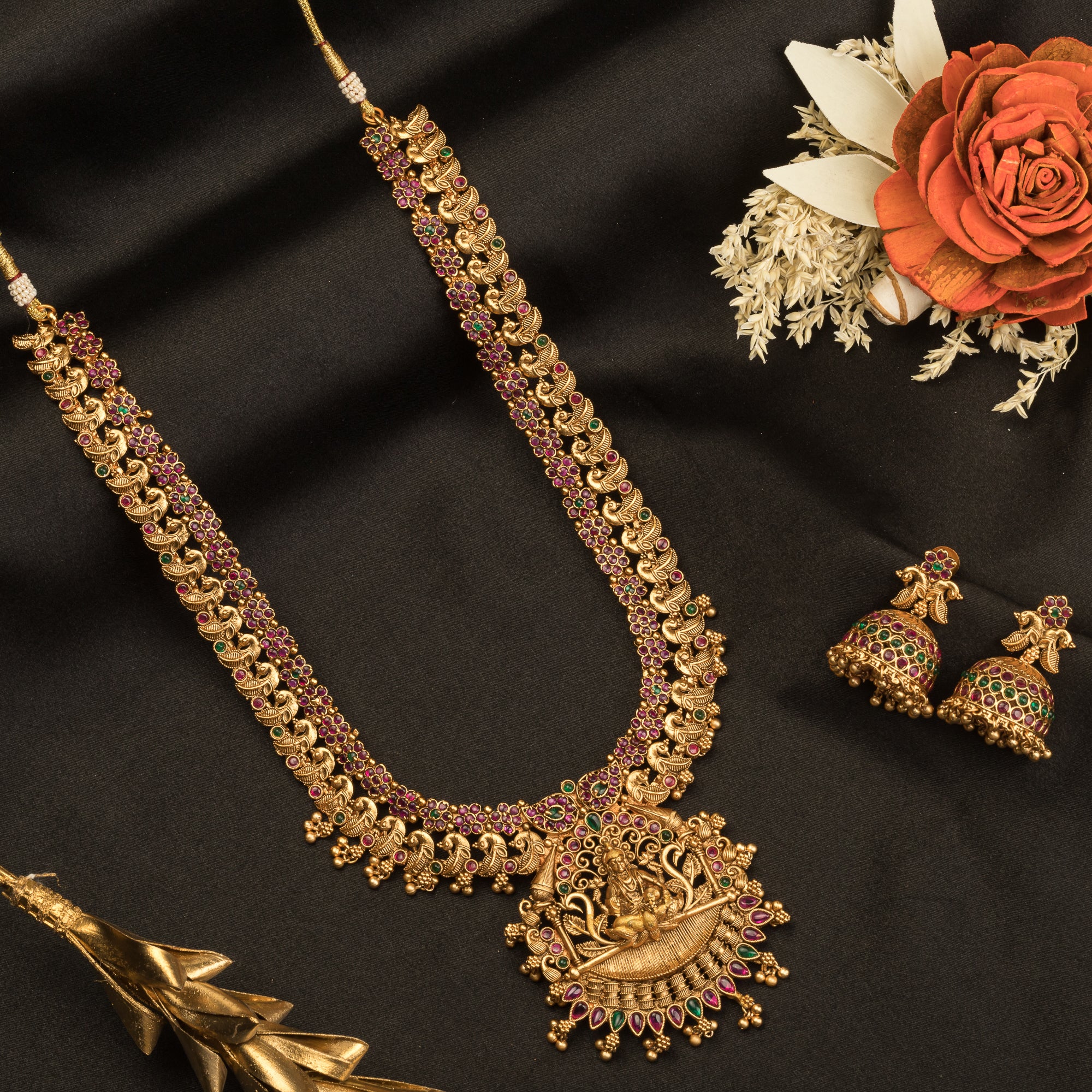Traditional temple jewelry with red and green stones radiates timeless opulence and charm.