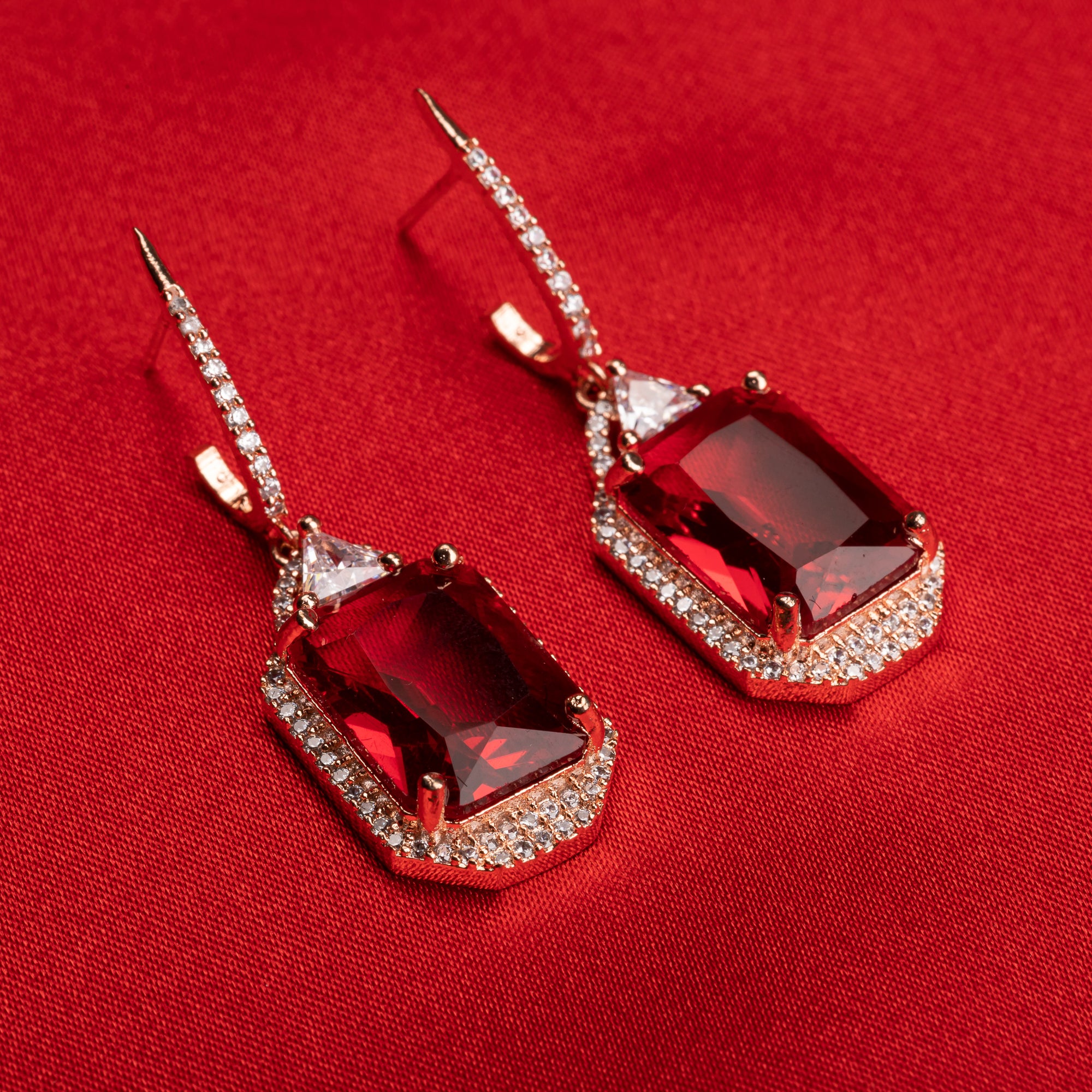 "Dark red zircon dangler earrings in rose gold offer a bold, sophisticated touch for party wear."
