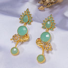 "Gold-tone dangler earrings with light green accents blend warmth and freshness for a chic, eye-catching festival look."
