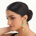 "Gold-tone dangler earrings with light green accents blend warmth and freshness for a chic, eye-catching festival look."
