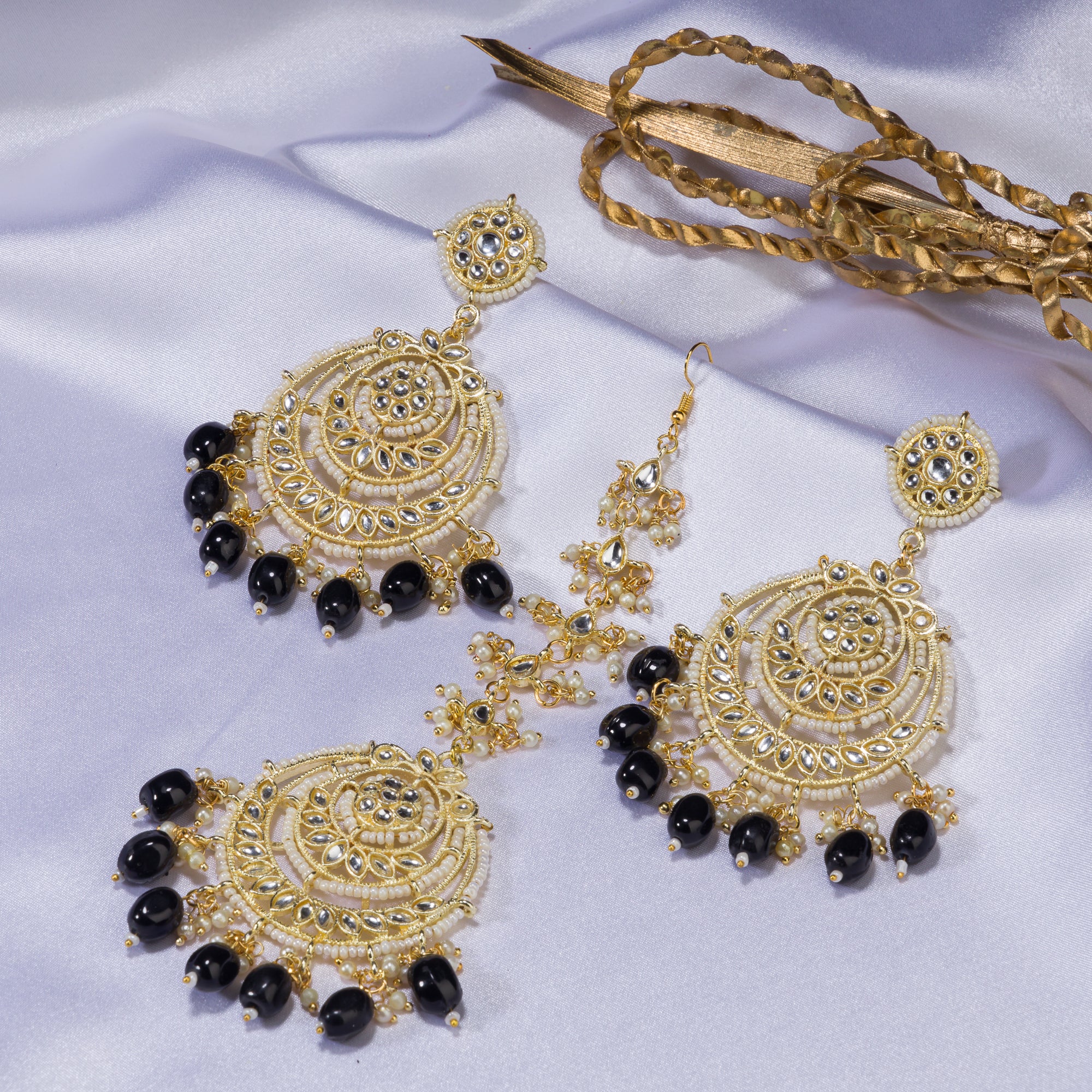 "Black kundan earrings with gold polish and matching maangtika exude regal sophistication."
