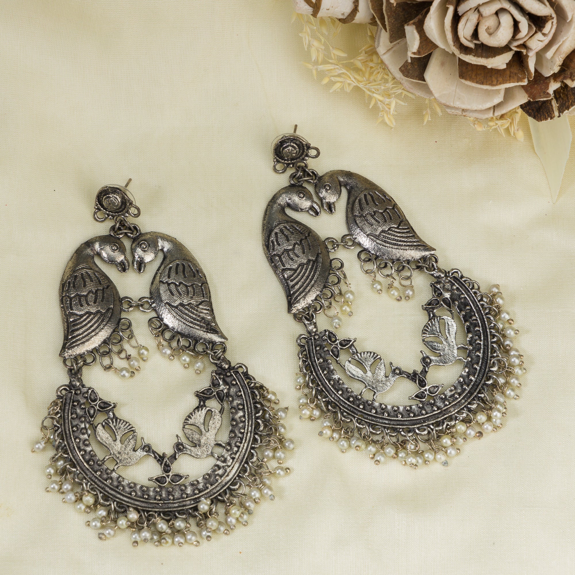 "Small oxidized earrings with two birds add vintage charm with intricate details."
