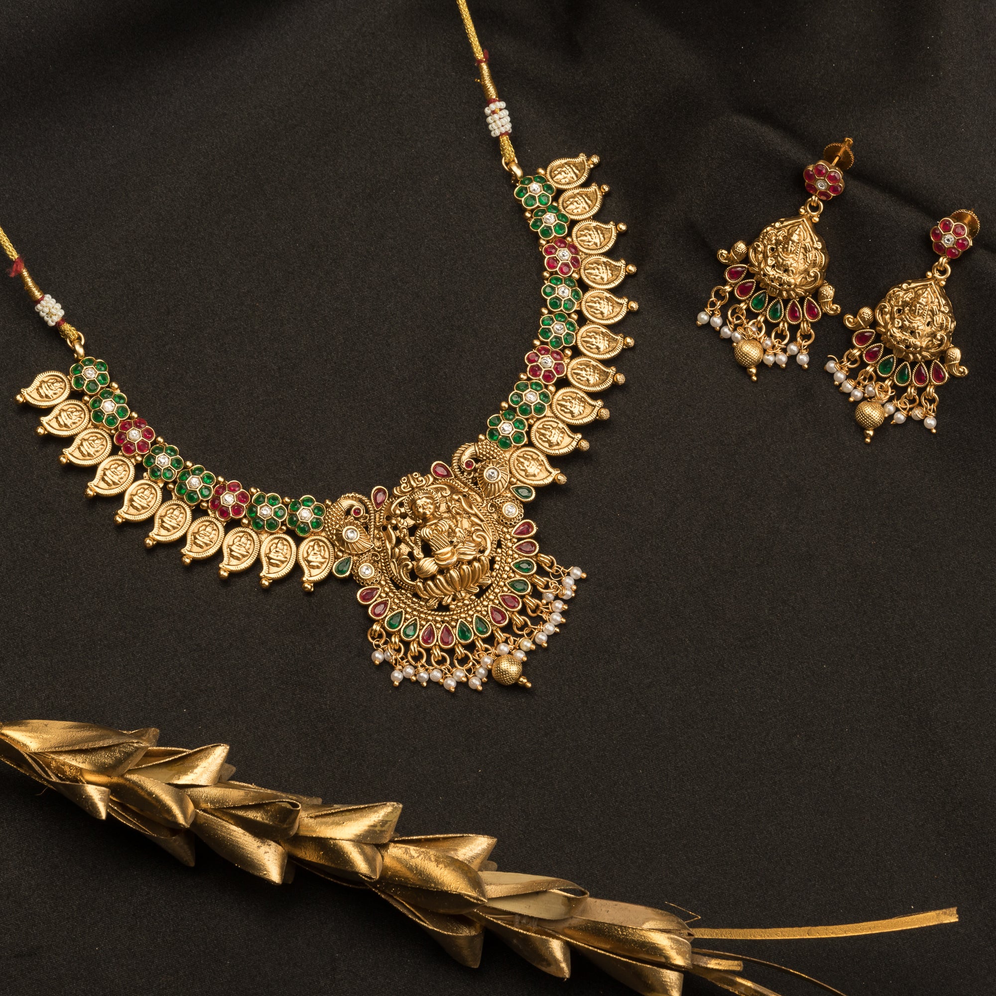 Intricate temple jewelry in red, gold, and green brings classic elegance to festival occasions.
