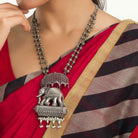 "Oxidized long necklace with umbrella, elephant motifs, and white pearls exudes vintage elegance."
