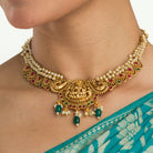 "Gold-tone necklace with white pearl and green Kundan for a timeless traditional look."

