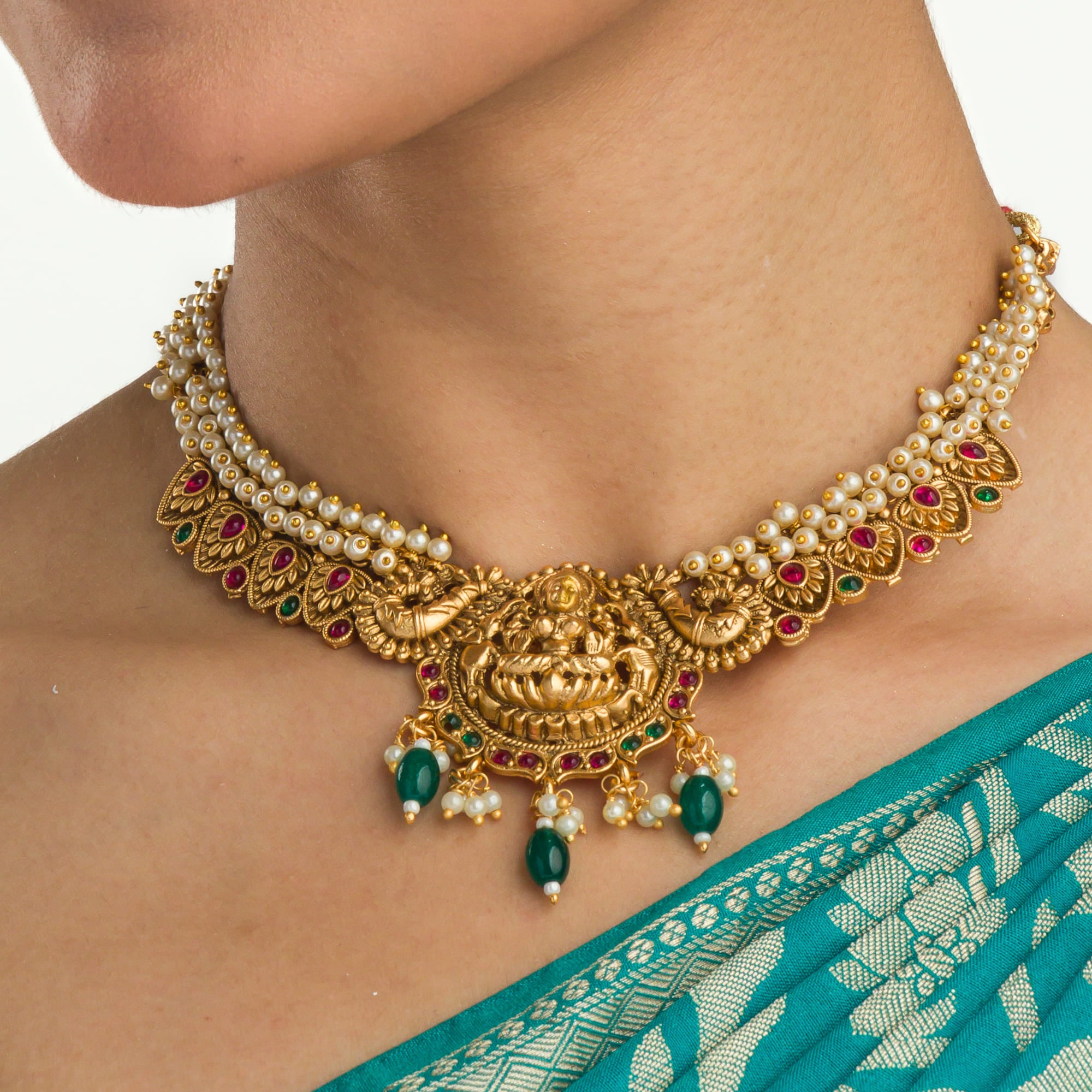 "Gold-tone necklace with white pearl and green Kundan for a timeless traditional look."
