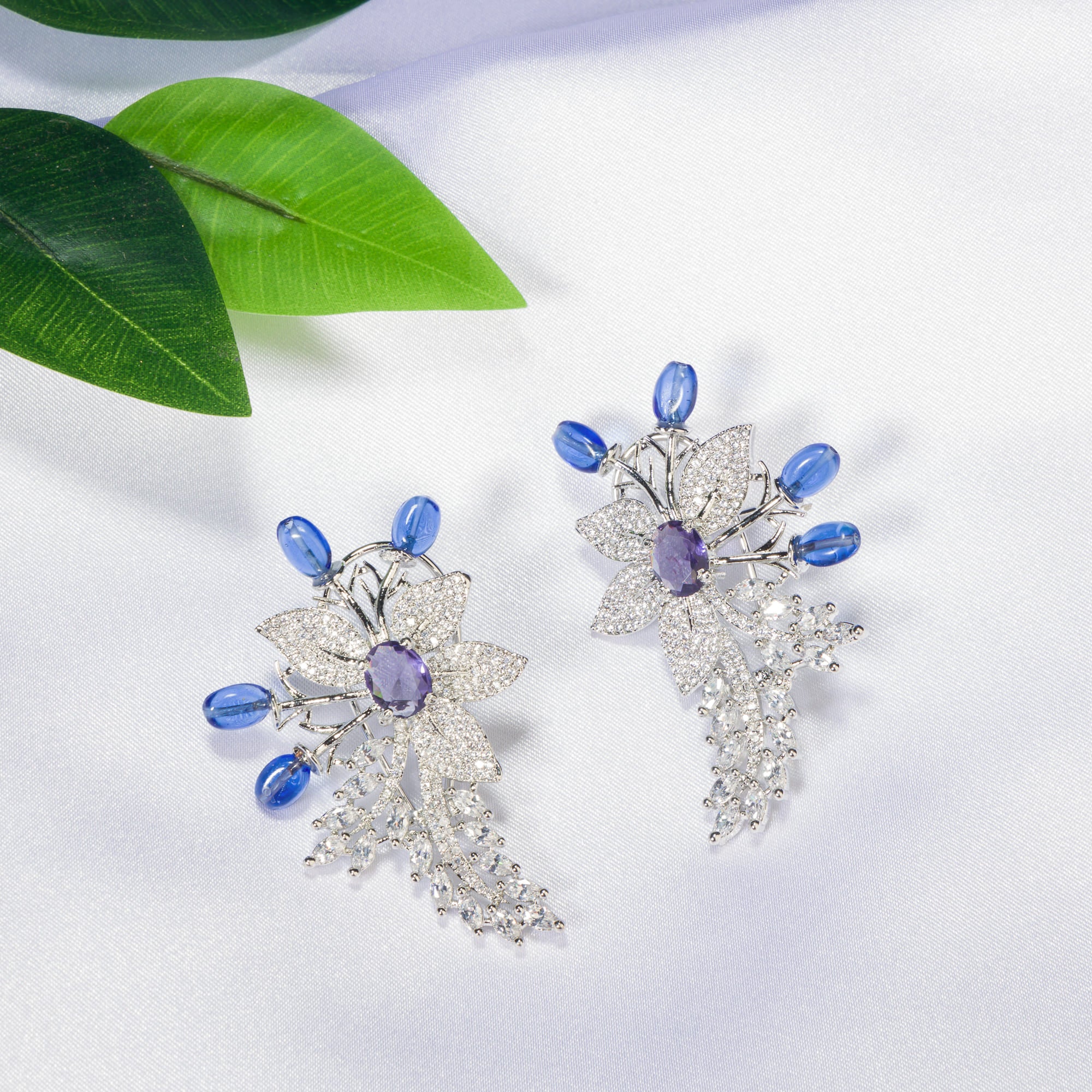"Zircon flower-shaped earrings with a blue zircon center add vibrant sparkle."
