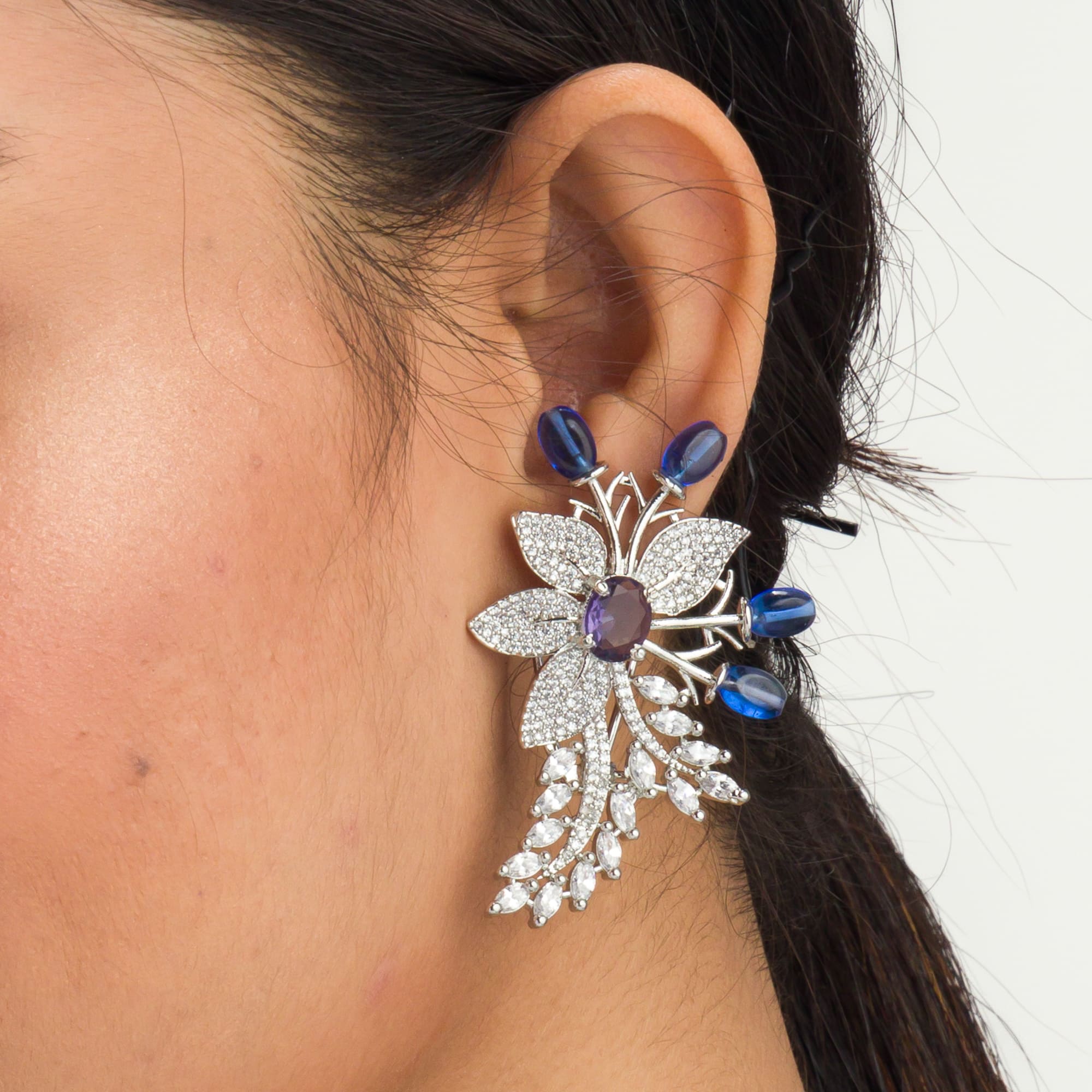 "Zircon flower-shaped earrings with a blue zircon center add vibrant sparkle."
