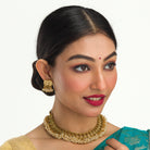 Gold-tone necklace with coin design and pearls exudes timeless elegance.
