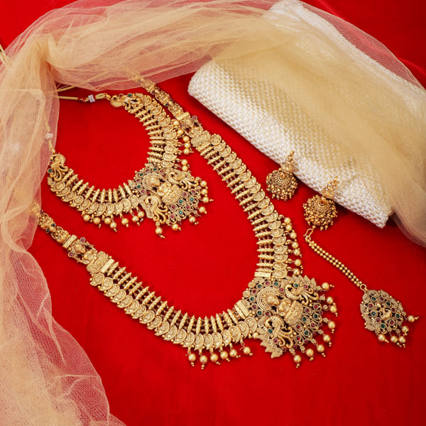 "Goldtone Laxmi Maa crafted long necklace set with matching earrings and Maang Tikka for festive elegance."
