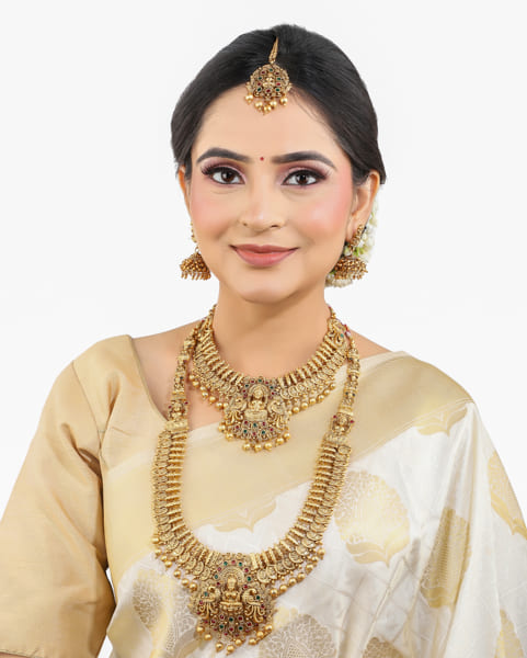 "Goldtone Laxmi Maa crafted long necklace set with matching earrings and Maang Tikka for festive elegance."
